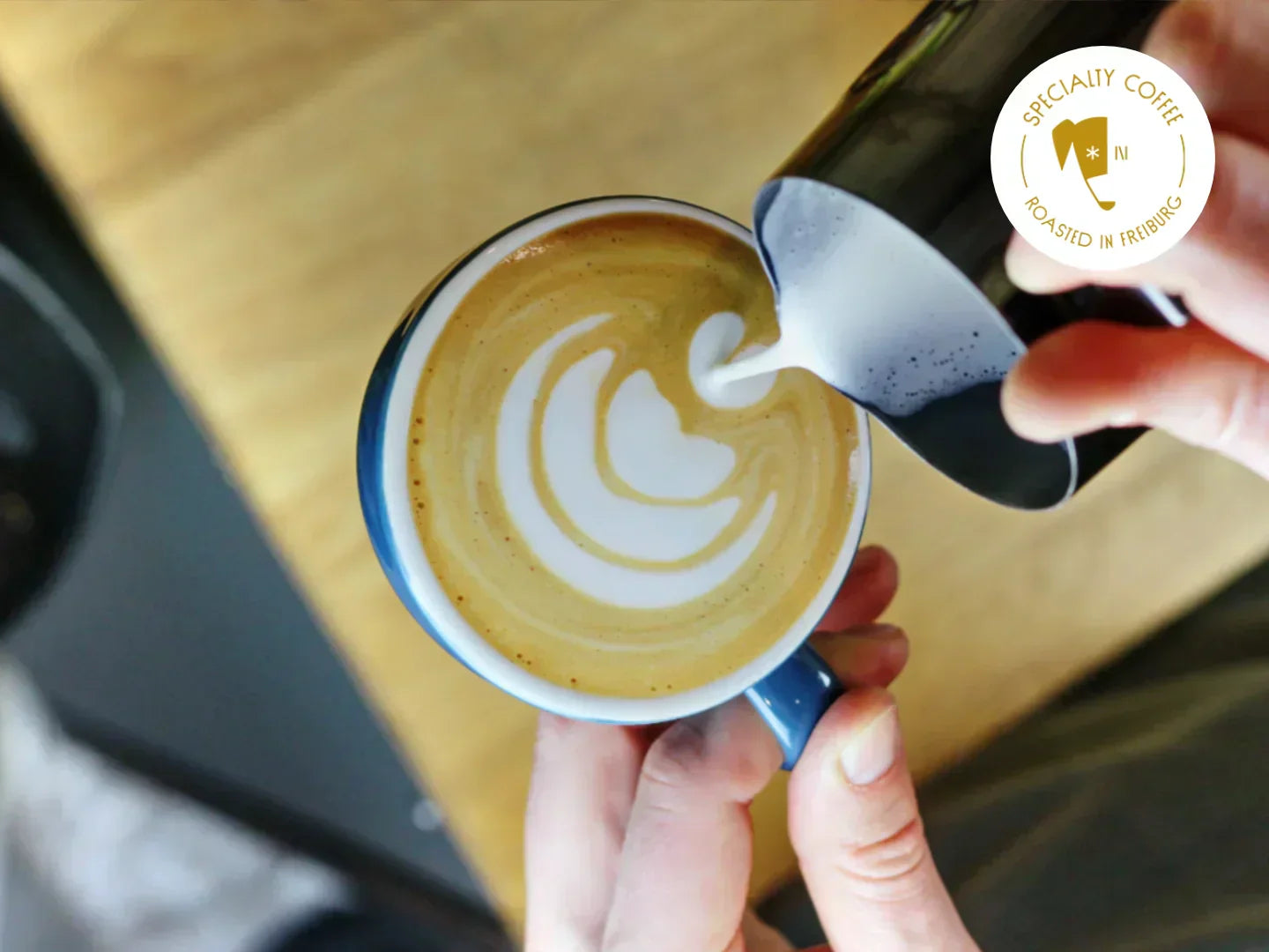 Titelbild zum Blogartikel über Latte Art. Zu sehen ist, wie Mats eine Tulpe in einen Espresso gießt.