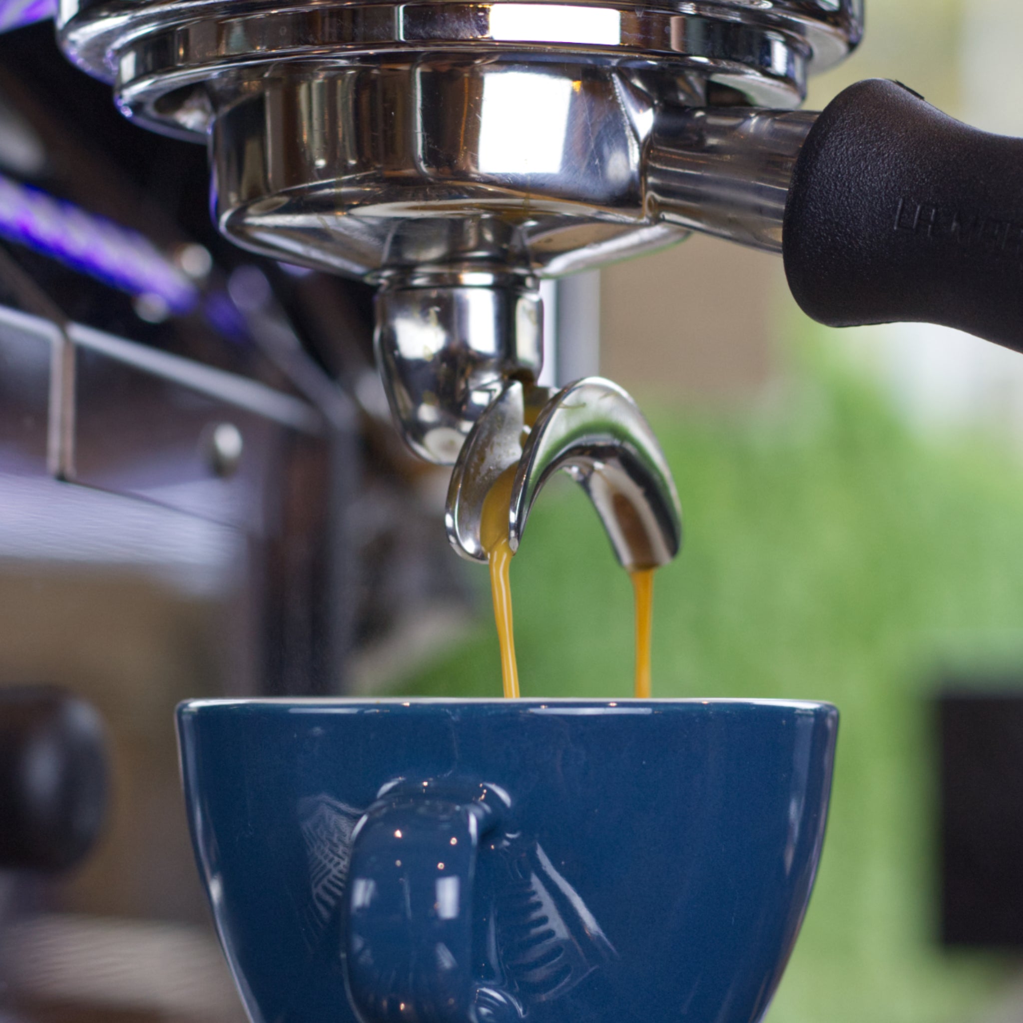 Leckerer Kaffee läuft vom Siebträger in eine blaue Tasse.