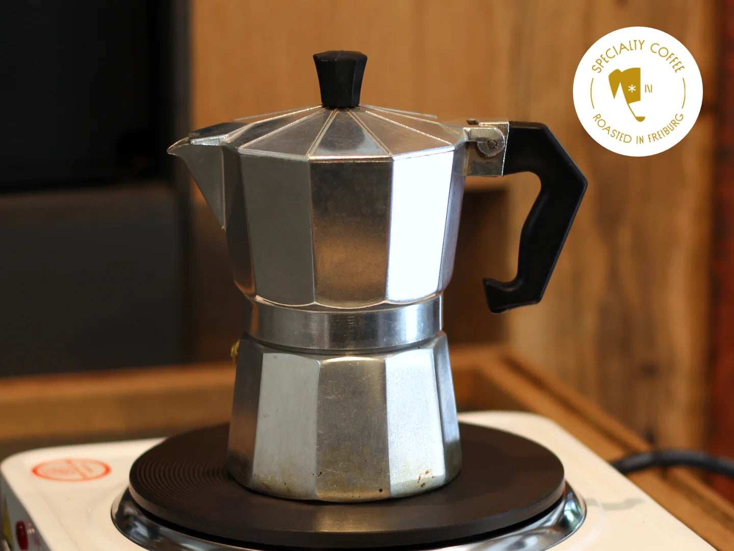 Titelbild zum Artikel über die Kaffeezubereitung mit dem Espressokocher. Zu sehen ist ein typischer achteckiger Espressokocher aus Aluminium auf einer Herdplatte.