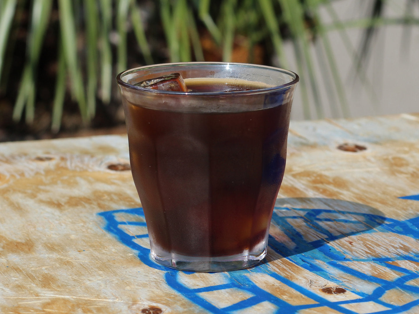 Titelbild zur Anleitung für Cold Brew. Zu sehen ist ein Cold Brew in einem 250-ml-Glas auf einem Tisch des Café Marcel.